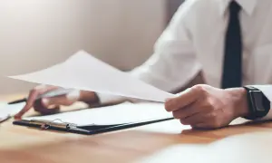 Dłoń trzyma dokumenty, analizując wielkość nabywanego udziału w prawie majątkowym.