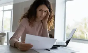 Zmartwiona kobieta analizuje dokumenty, rozważając odrzucenie spadku.