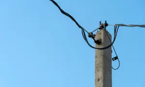 Betonowy słup energetyczny z przewodami. Zastanawiasz się, ile wynosi odszkodowanie za słupy energetyczne na działce?
