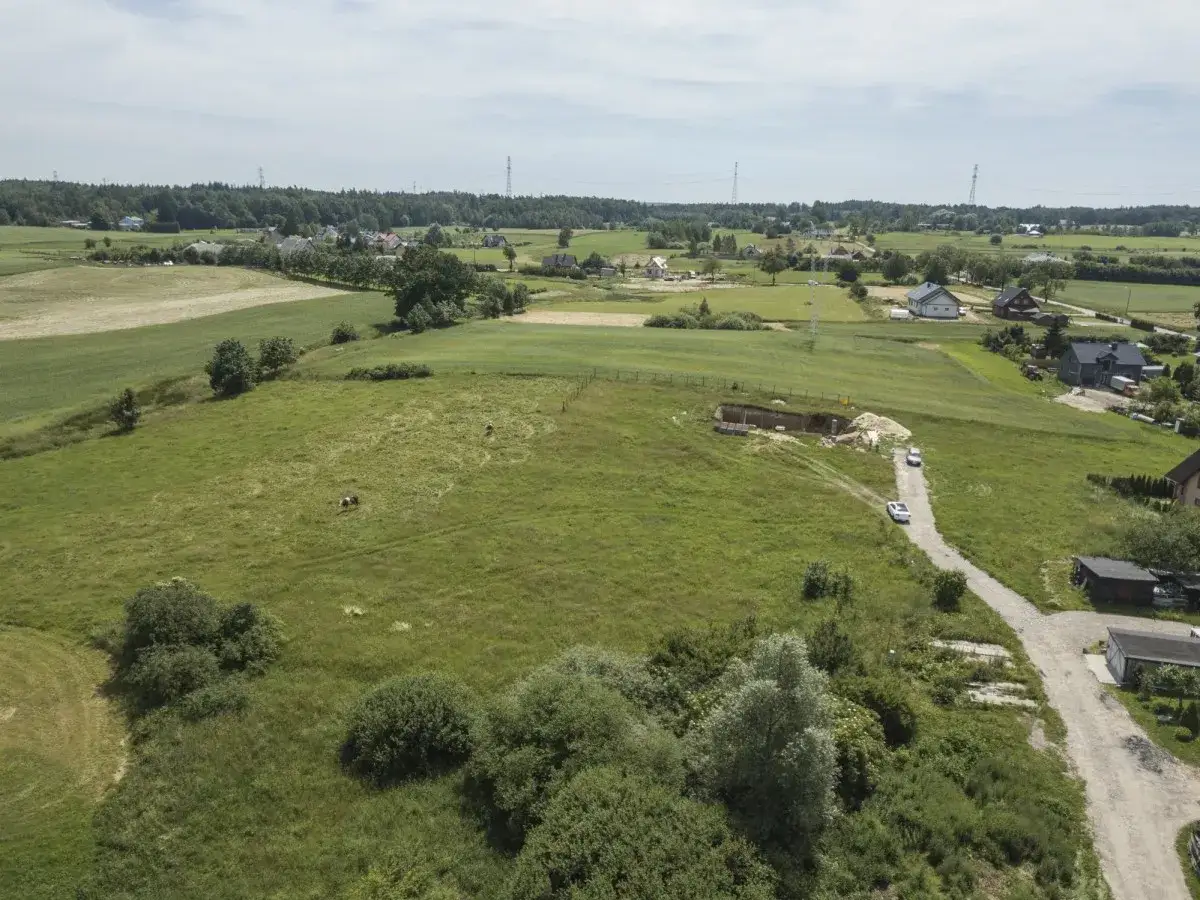 Krajobraz wiejski z polami, domami i drogą. Widać wykop pod budowę, który może być związany z przyszłą inwestycją, a więc i z rentą planistyczną.