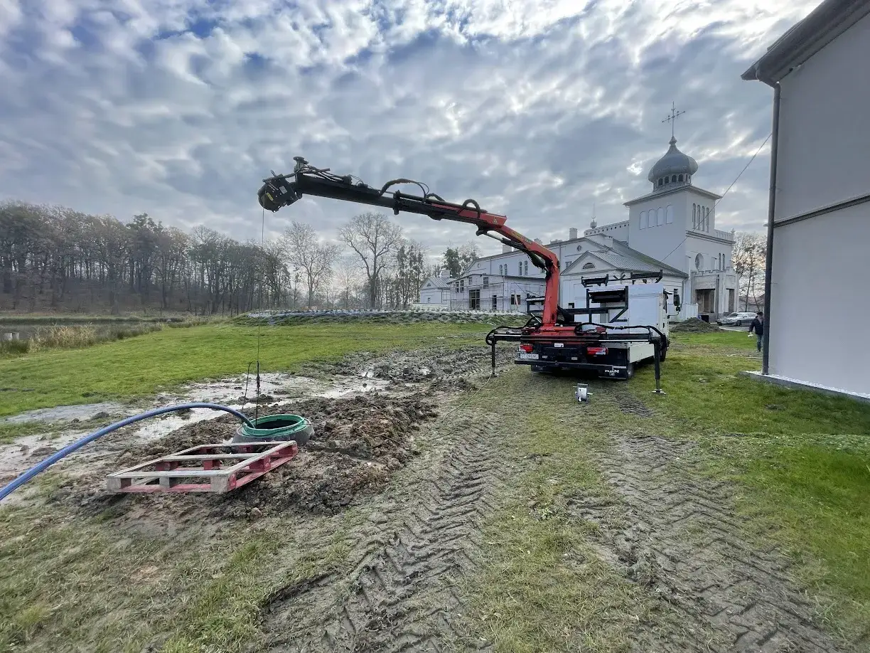 Dźwig pracuje przy studni głębinowej. Trwa montaż, który wpłynie na studnia głębinowa koszt.
