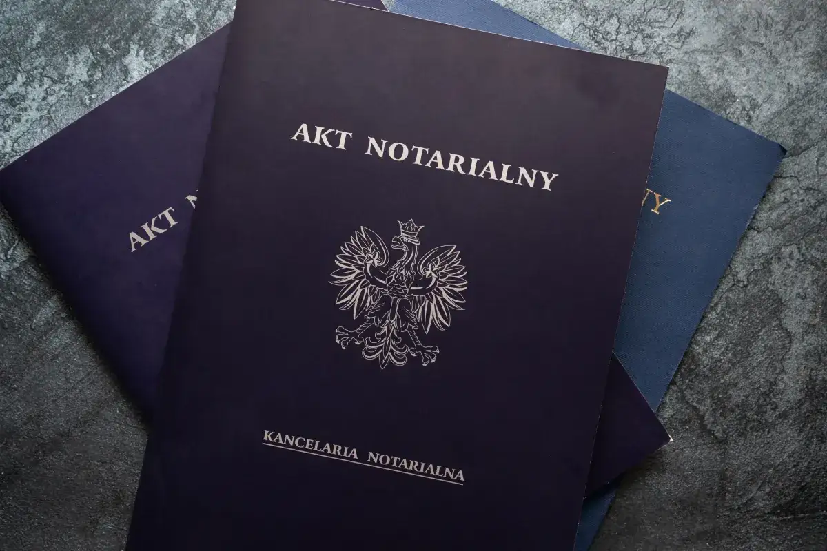 Akt notarialny, który może dotyczyć ustanowienia służebności mieszkania, leży na kamiennym blacie obok innych dokumentów.