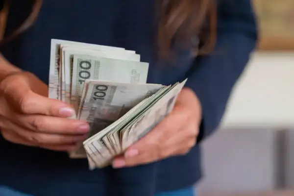 Dłonie liczą banknoty 100 zł. To może być darowizna od rodziców, która mieści się w limicie.