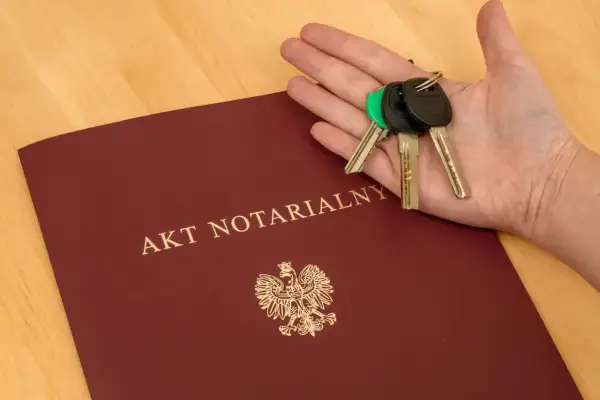 Akt notarialny i klucze w dłoni. Dokument z godłem Polski, symbolizuje finalizację transakcji, jak zakup mieszkania. To ważny wpis do repertorium.