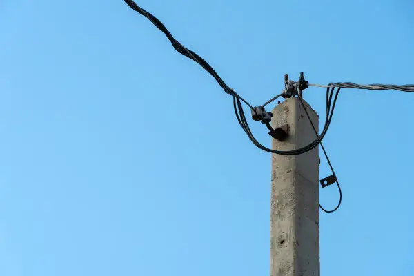 Betonowy słup energetyczny z przewodami. Zastanawiasz się, ile wynosi odszkodowanie za słupy energetyczne na działce?